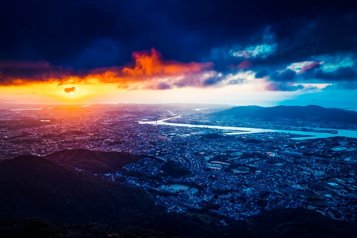 Cityscape at sunset with dramatic clouds over a river
