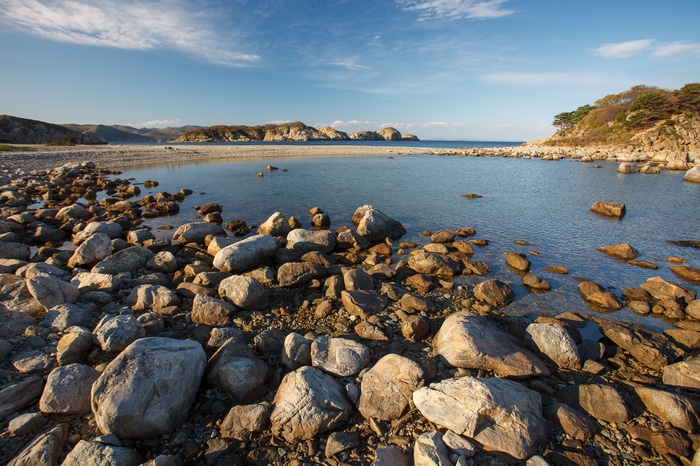 Rocky coastline with calm water and distant hills