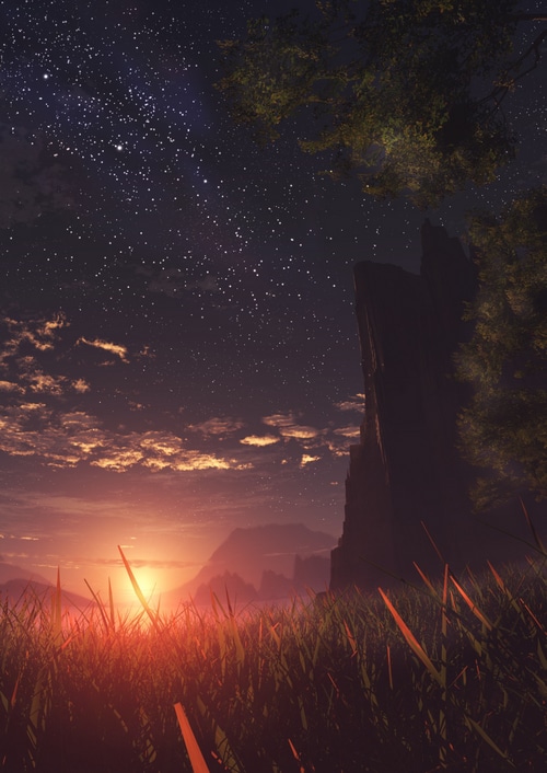 Sunset over a grassy landscape with a rocky outcrop