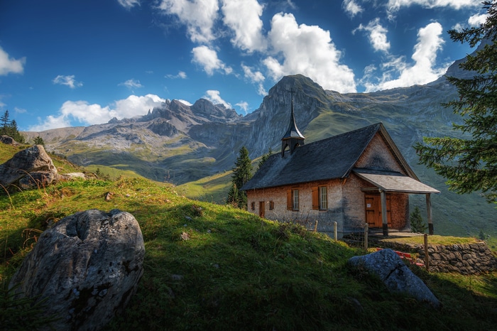 Chapel in the Swiss Alps with Mountains and Clouds