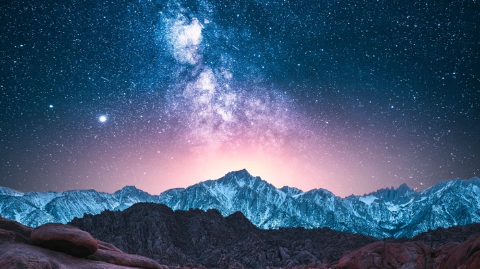 4K Milky Way over snow-capped mountains at sunset
