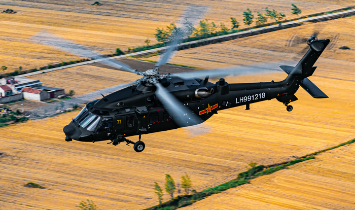 Chinese Z-20 helicopter flying over farmland