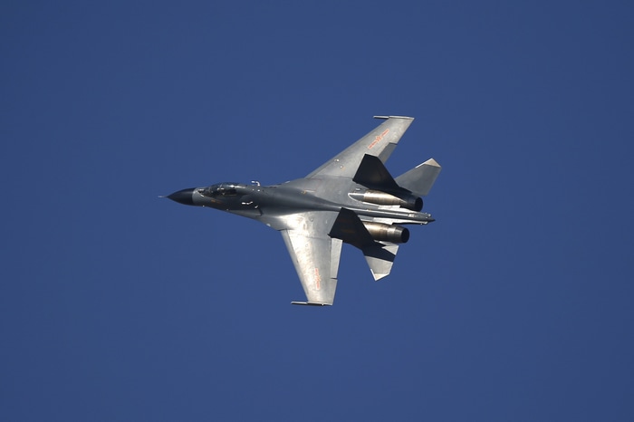 Chinese J-11 fighter jet flying in blue sky