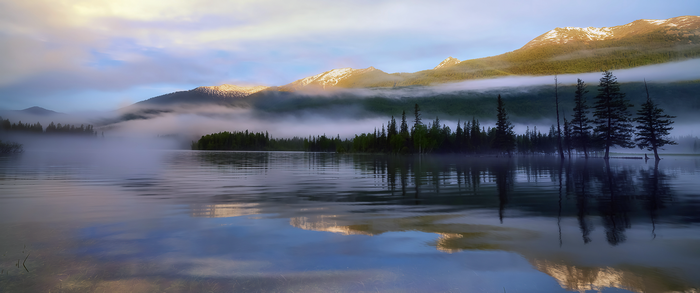Misty mountains reflected in a calm lake