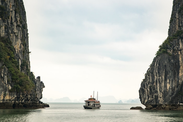 Boat sailing between limestone karsts in Ha Long Bay