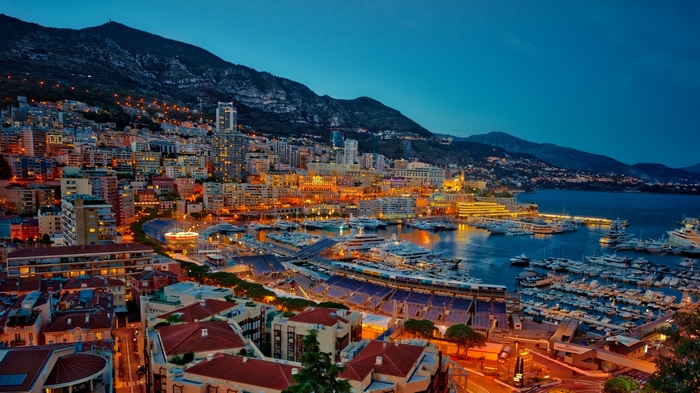 4K Monaco cityscape with yachts and mountains at dusk