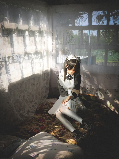 Anime girl in a maid outfit sitting on a bed