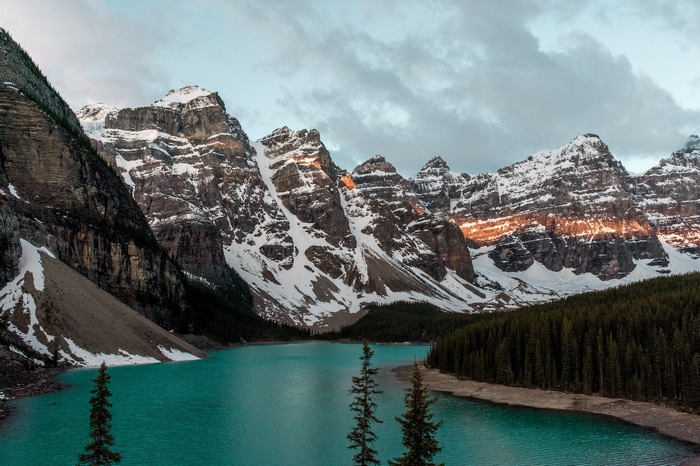 Turquoise lake and snow-capped mountains with a forest