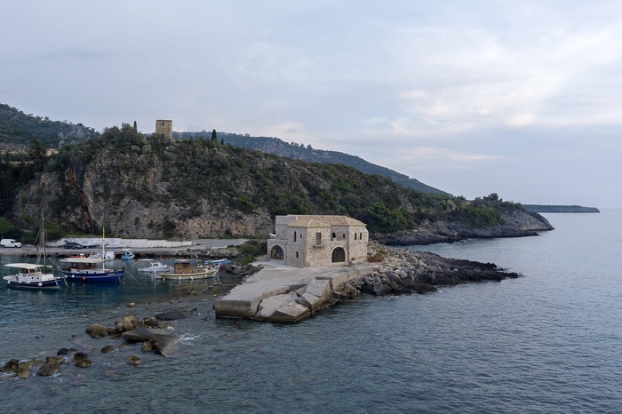 Stone building on a rocky peninsula in a harbor with boats