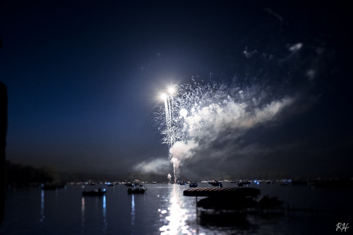 Fireworks over a lake with boats