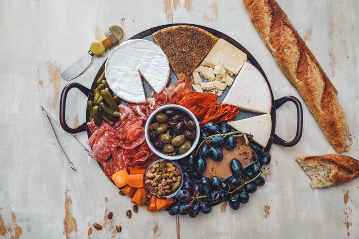 Charcuterie board with cheese, salami, olives, grapes, and bread