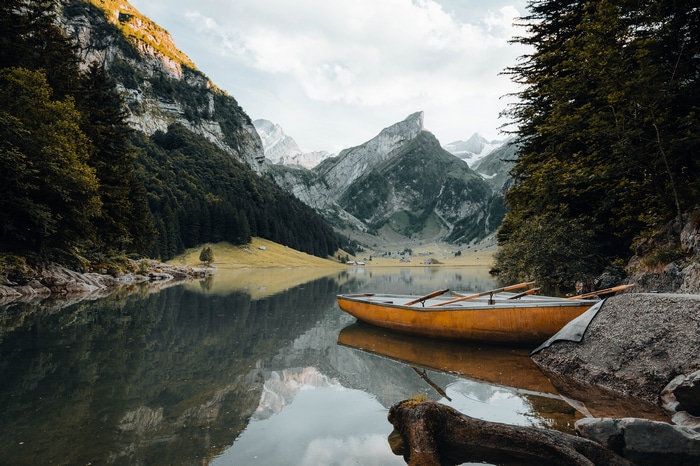 Boat on a lake with mountains and forest reflection