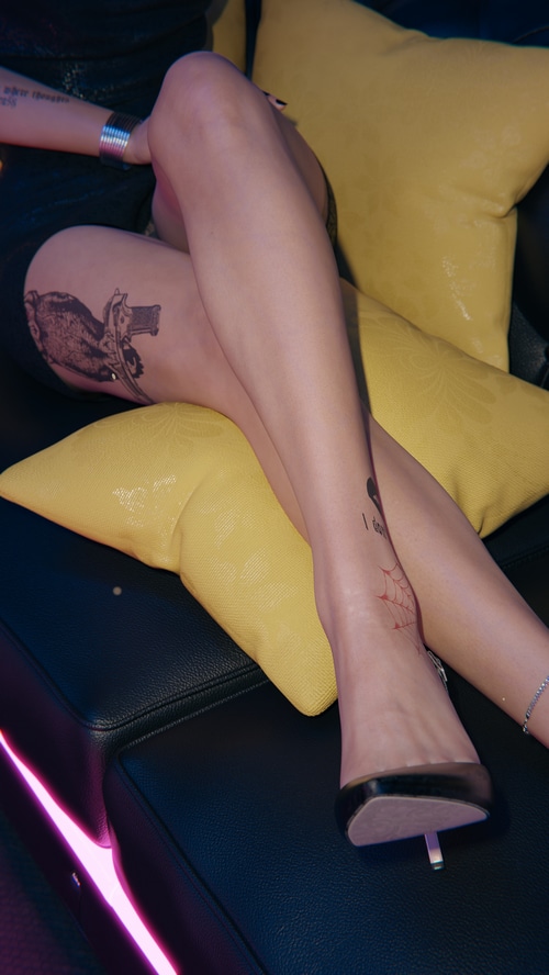 Woman with tattoos wearing black high heels on a couch