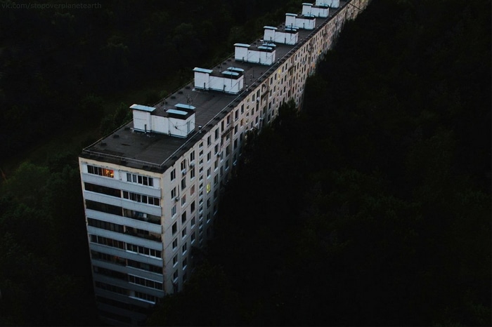 Long block of flats in a dark forest in Russia