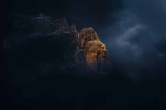 Sunlit mountain peak emerging from dark clouds