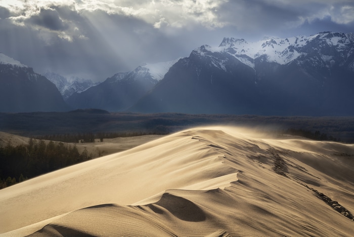 Sand dunes with mountains and sun rays