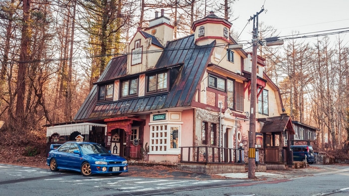 Blue Subaru Impreza parked in front of a unique building in Japan