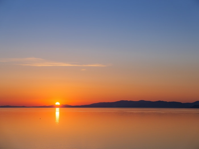 Sunset over the sea with mountains in the background