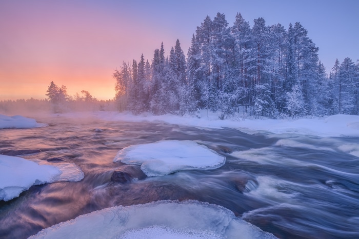 Winter river with snow-covered trees and sunrise sky