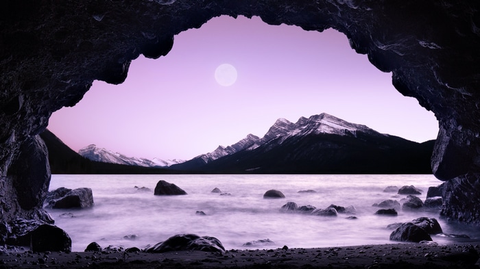 Cave view of mountains and lake with moon