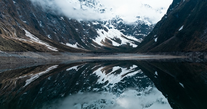 Snowy mountains reflected in a lake with clouds