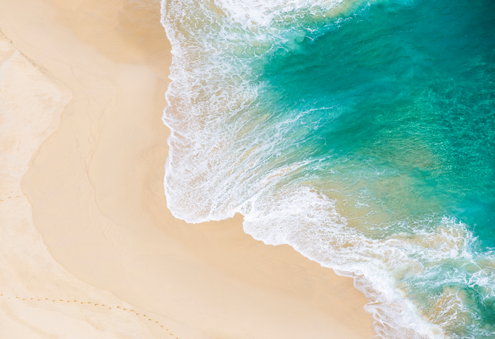 Aerial view of a sandy beach with turquoise ocean waves