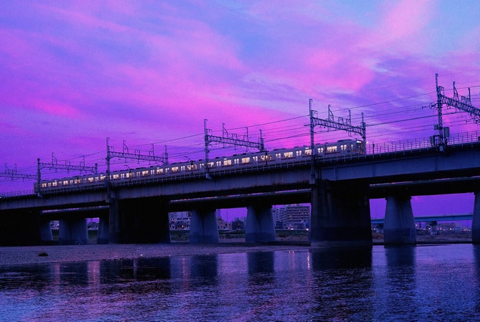 Train crossing a bridge under a purple sky