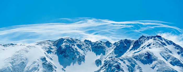 4K snow-covered mountains with wind-blown clouds