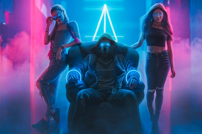 Man in mask with two women in neon club