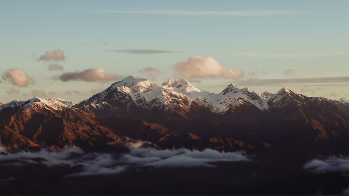 Snow-capped mountains at sunset with clouds