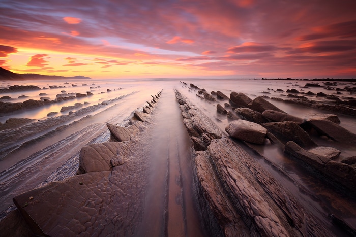 Sunset over a rocky beach with ocean waves