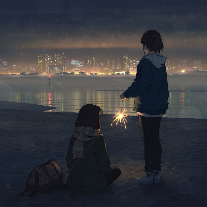 Two people with sparklers on a beach at night