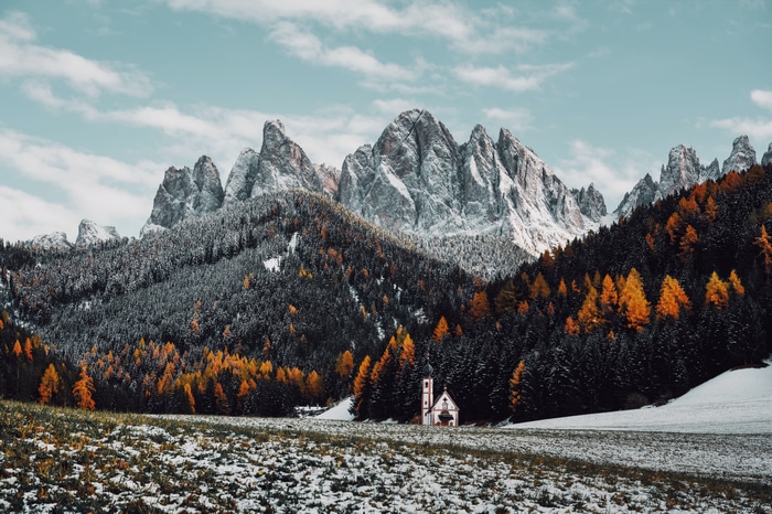 4K snow-covered mountains with a church and autumn trees