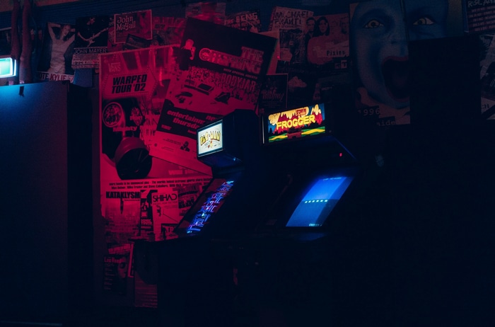 Arcade cabinets with Frogger and Pac-Man in a dark room