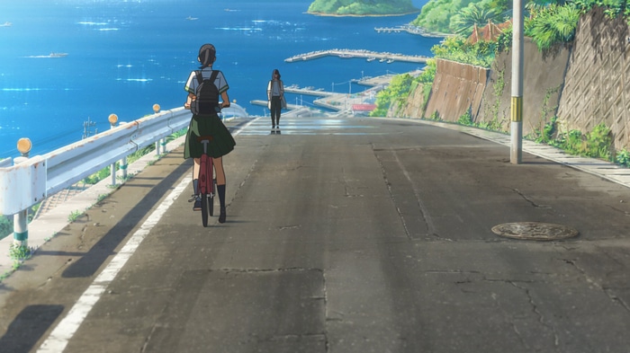 Two girls in school uniforms on a road by the sea