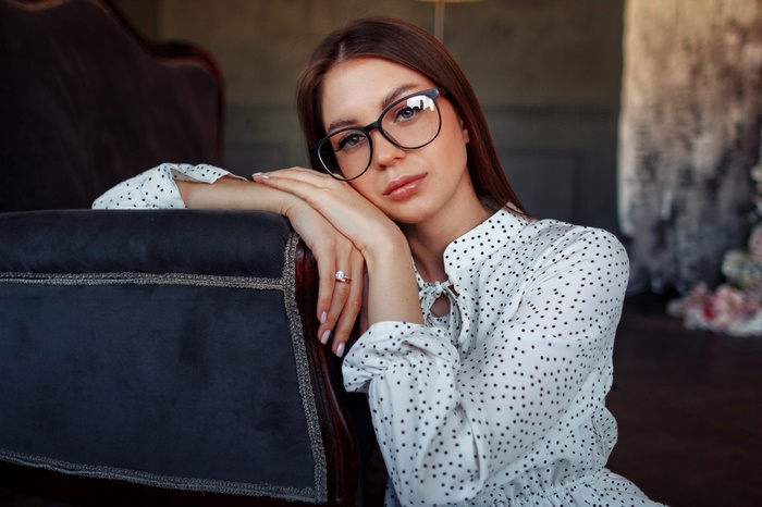 Woman with glasses leaning on a couch
