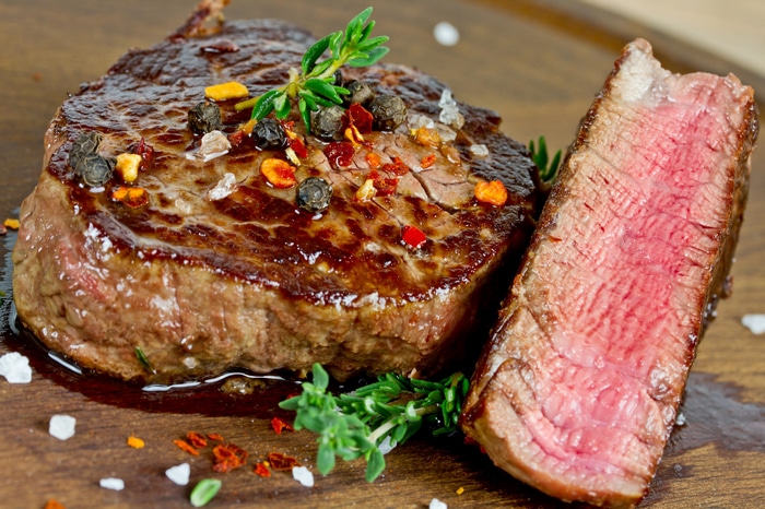 4K close-up of a seasoned steak with herbs