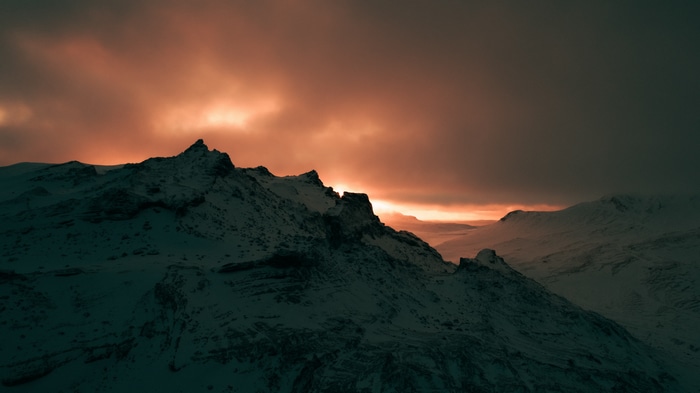Snowy mountains under a dramatic sunset sky