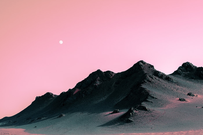 Moon over dark mountains in a pink sky