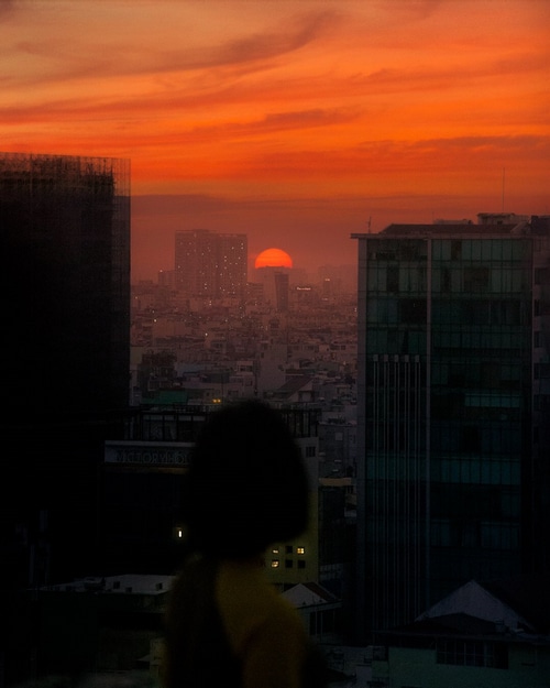 Silhouette of a person watching a sunset over a cityscape