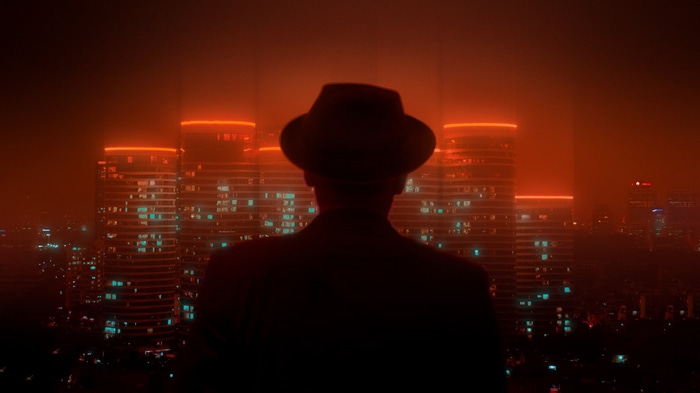 Silhouette of a man in a hat overlooking a neon cyberpunk cityscape