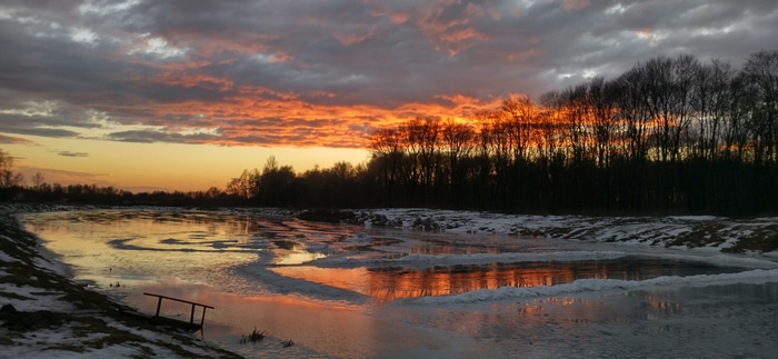 4K sunset over a partially frozen lake in winter