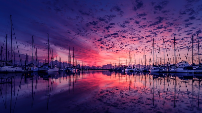4K sailboats in a harbor at sunset with reflection