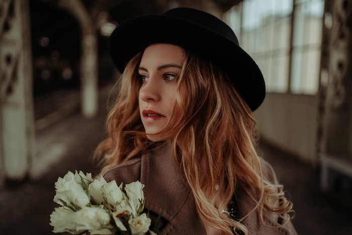 Woman in Hat Holding White Roses
