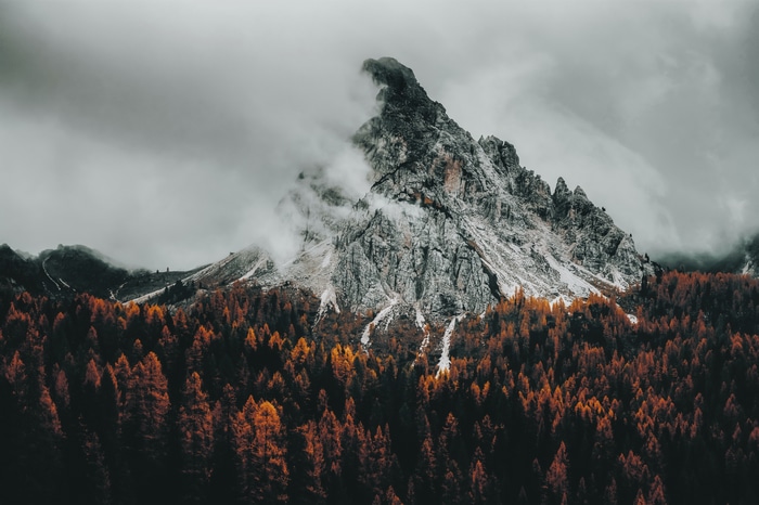 4K cloudy mountain peak above autumn forest