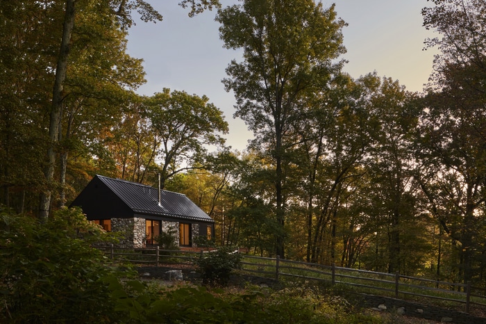 Stone and black house in a forest with a fence