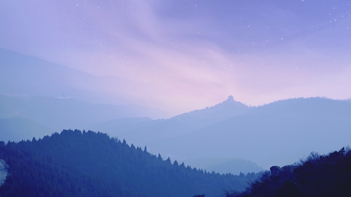 Misty mountains with a building on a peak