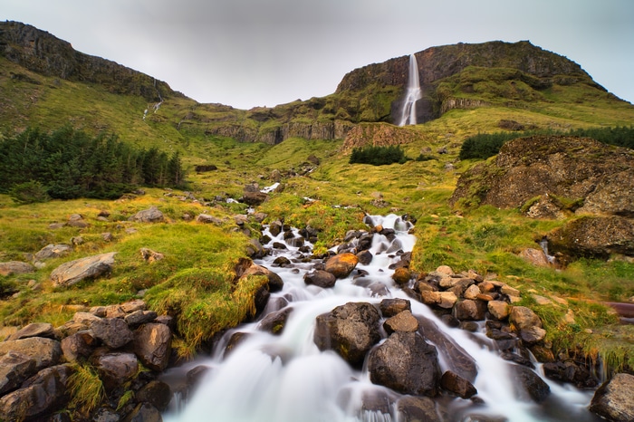 Waterfall cascading down a rocky, moss-covered mountainside in Iceland