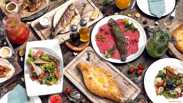 Table laden with Georgian food: khachapuri, fish, and salads