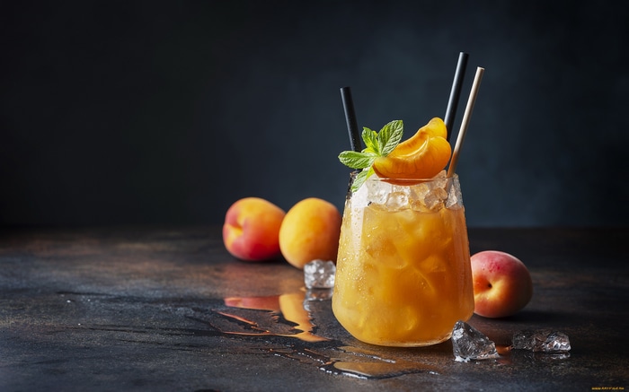 Peach cocktail with mint and peaches on a dark background